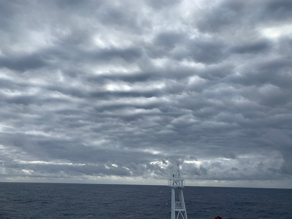 Dark clouds hang over the bow of the ship.